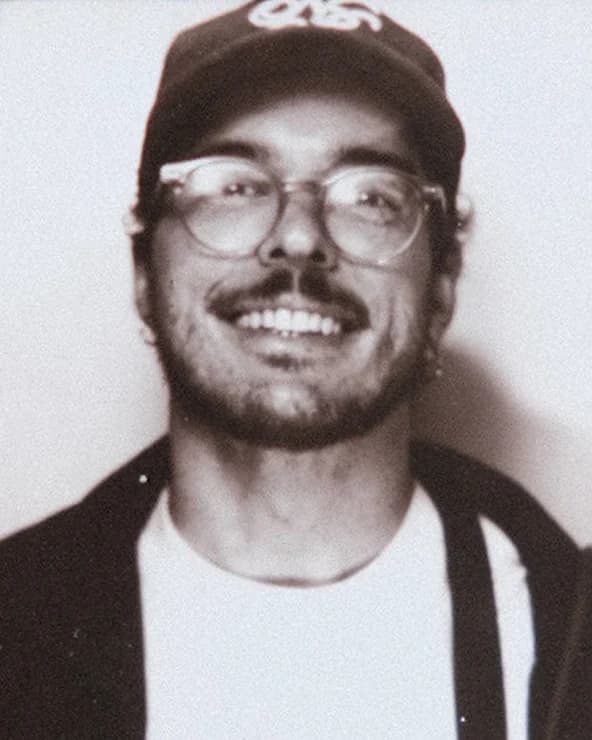 Portrait of Gabriel Pauli smiling, wearing a cap and glasses